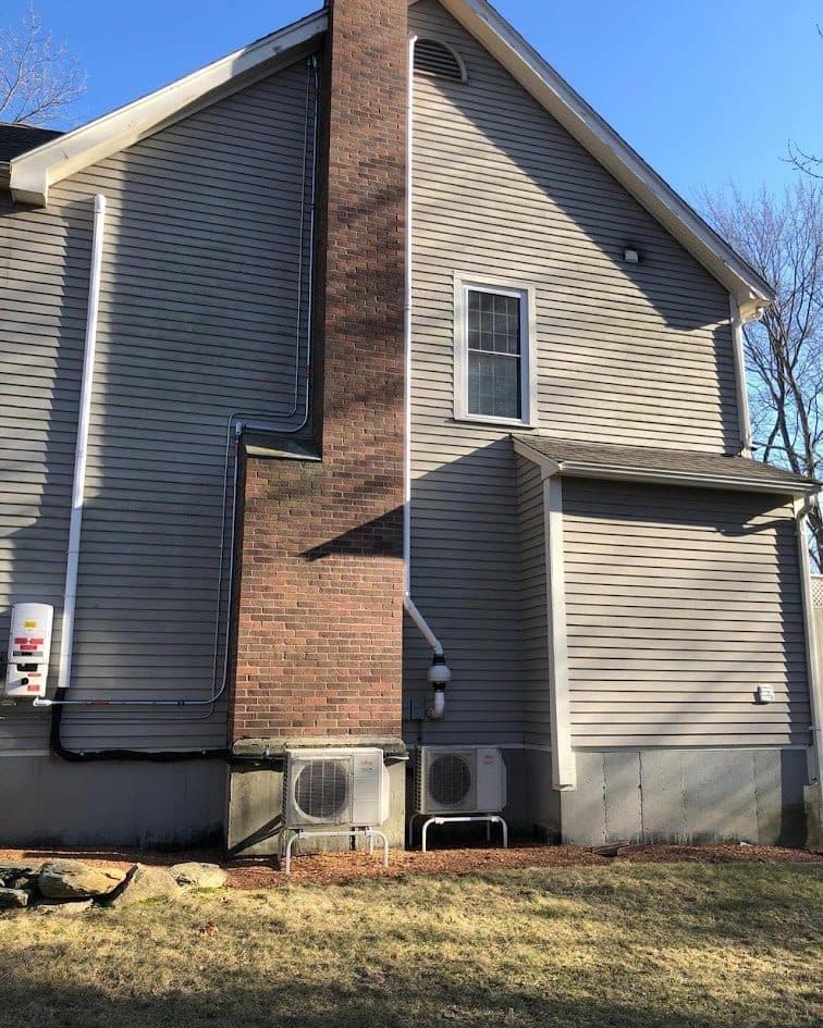 Gray house exterior with a brick chimney in a New England neighborhood